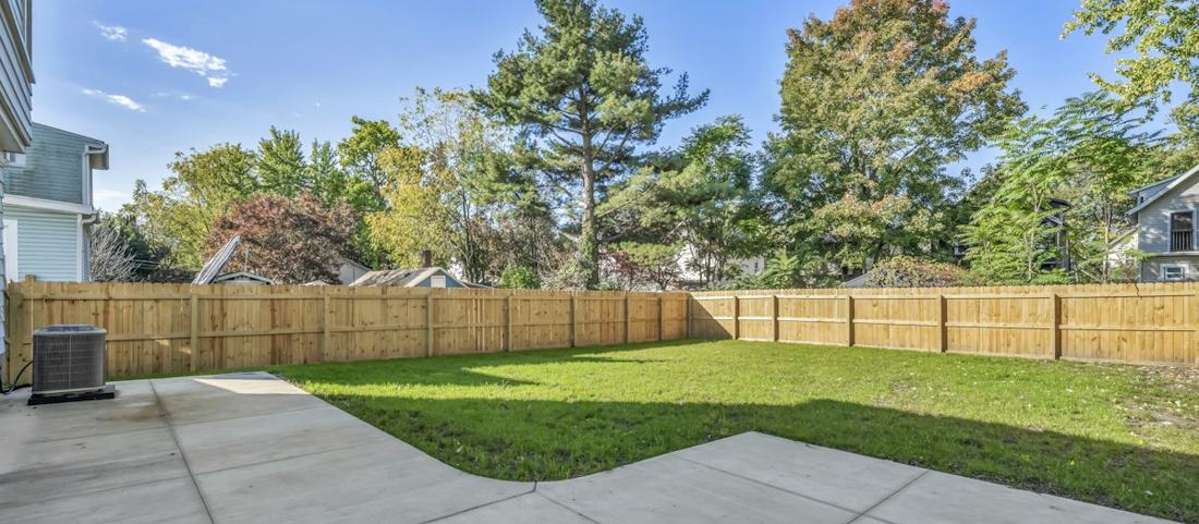 A fenced backyard with lawn and patio